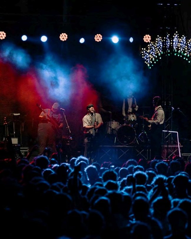 Band on stage in front of a large crowd at night