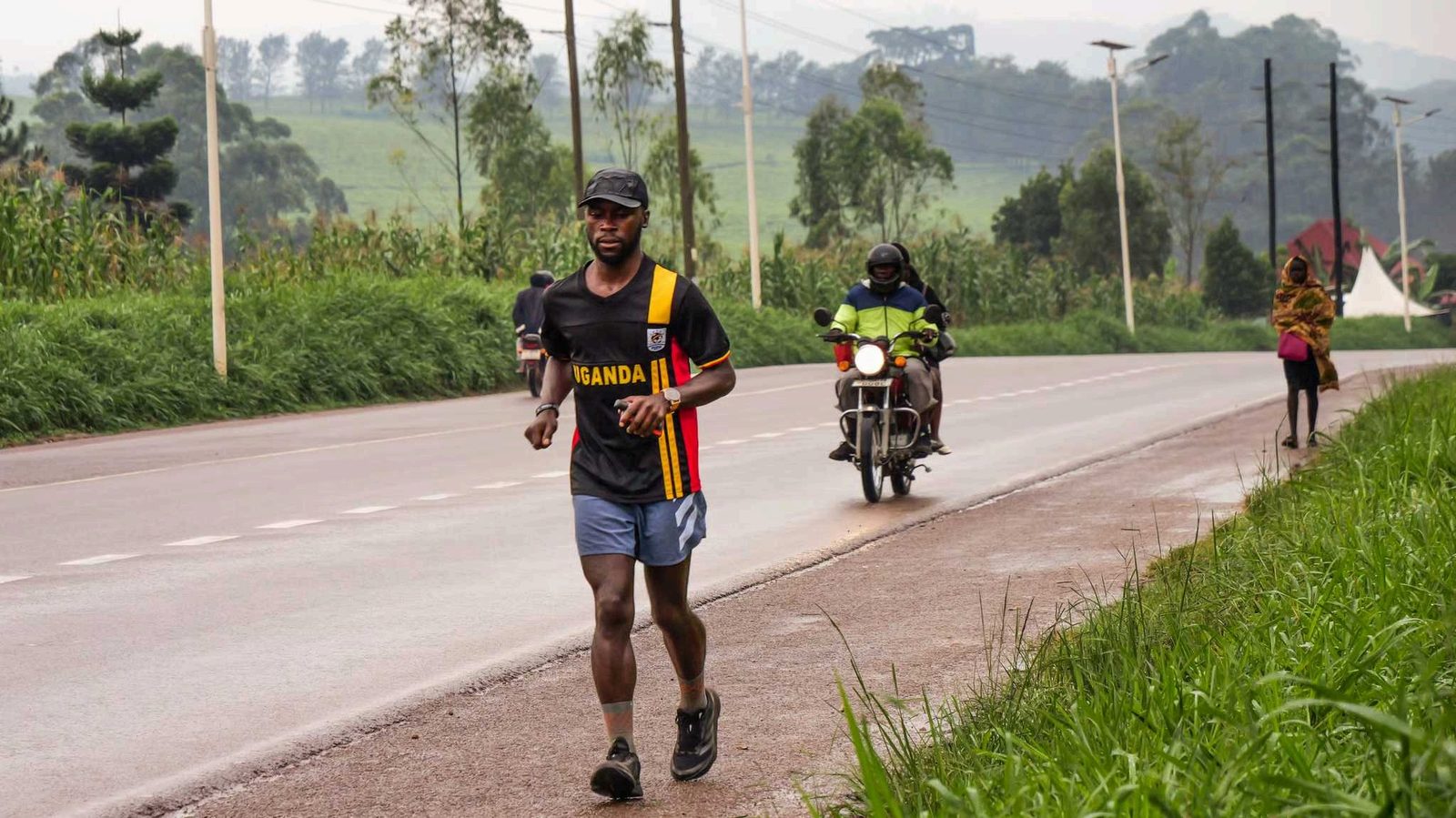Deo Kato running along a road, followed by a support motorbike